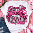 White graphic T-shirt laid flat with a pink and glitter memorial-style message reading 'Someone I love won in Victory and is now in HEAVEN! I wear pink for THEM,' surrounded by pink hearts, a ribbon, cross, butterfly, flowers, denim shorts, a pink Hope Care tumbler, a notebook, and pink sneakers on a pink textured background.